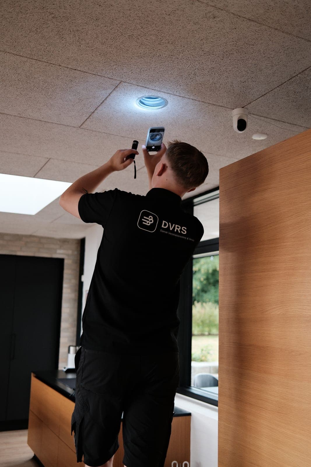 DVRS-tekniker kontrollerer ventilationsarmatur med lygte